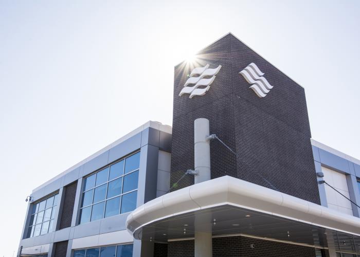 The sun shines down on the brick facade and Marine Atlantic wave logo of a modern looking office building/ferry terminal. 