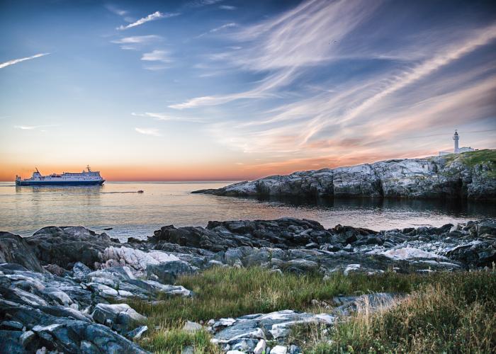 A ship sailing on the water near a lighthouse