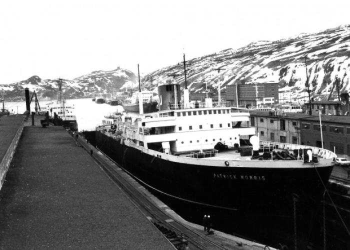 Ship docked with hills covered in snow in the background