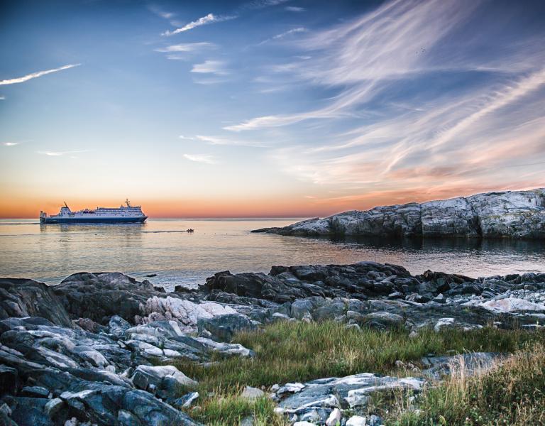 A ship sailing on the water near a lighthouse