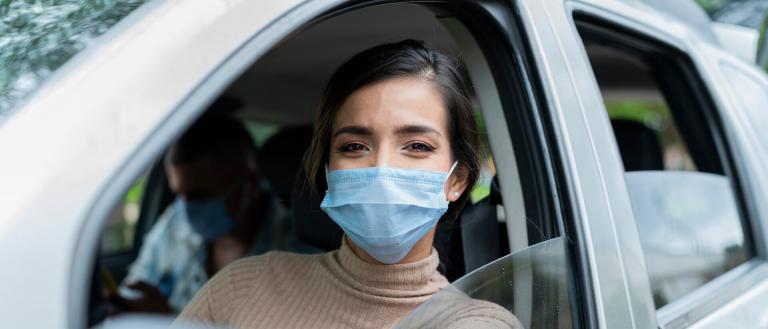 woman wearing blue mask while sitting in the car