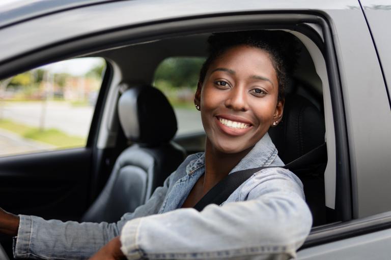 a woman sitting in her car smiling at the camera