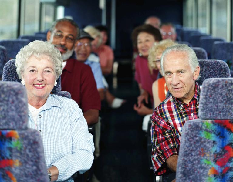 a group of seniors sit on a tour bus