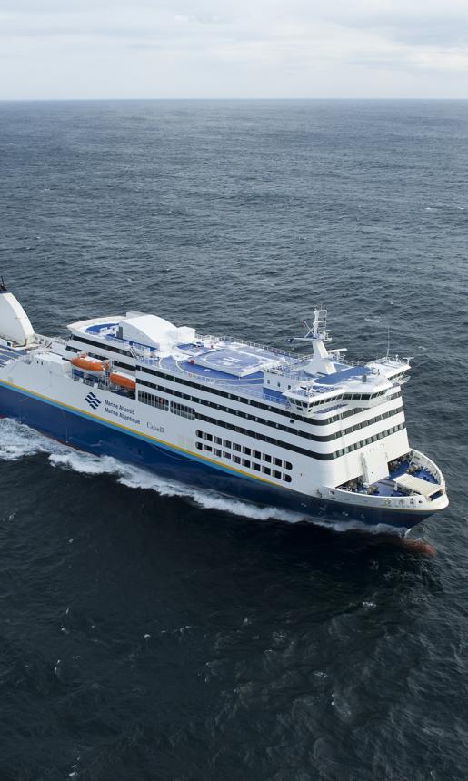 An aerial shot of a blue and white Marine Atlantic ferry as it sails in the middle of the Atlantic Ocean on a windy day.