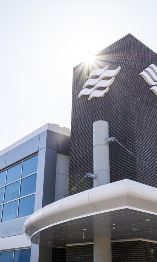 The sun shines down on the brick facade and Marine Atlantic wave logo of a modern looking office building/ferry terminal. 