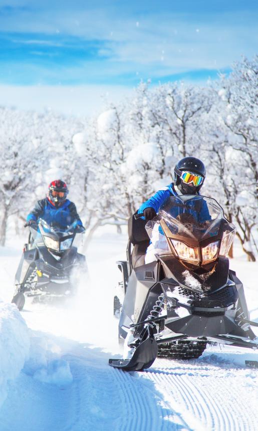 wo motorcyclists ride on a snowy road leaving uninterrupted traces on their way