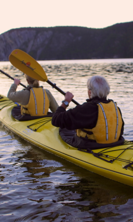 two people paddle in a yellow kayak on open water